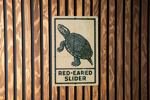 A sign with a turtle illustration and the text "RED-EARED SLIDER" is displayed on a wooden wall.