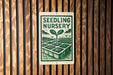 a sign for a seedling nursery, with a green and white design depicting a plant growing in a garden.
