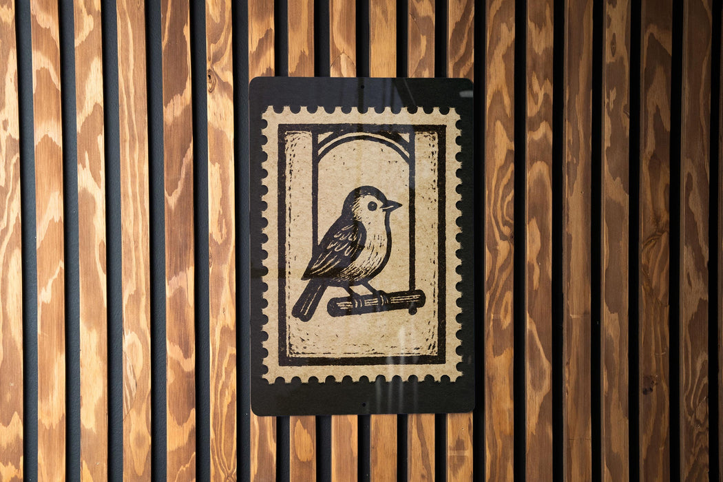 a wooden wall with a black and white postage stamp in the center, depicting a bird perched on a branch.
