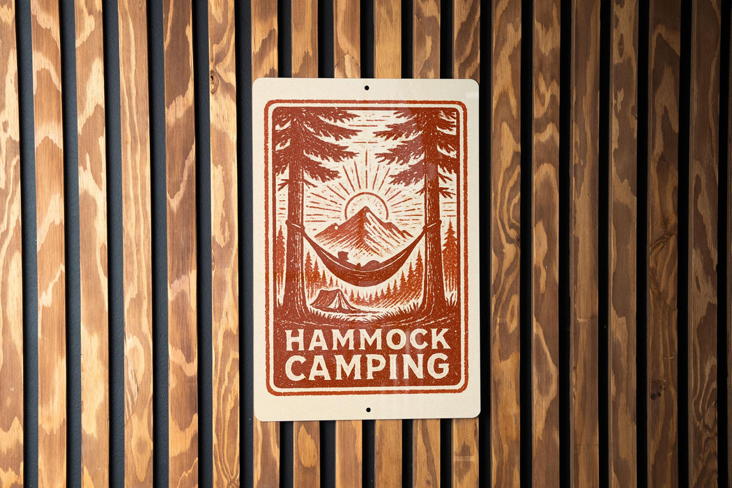 A sign with the text "HAMMOCK CAMPING" and an illustration of a hammock between two trees, with a mountain in the background.
