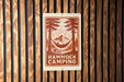 A sign with the text "HAMMOCK CAMPING" and an illustration of a hammock between two trees, with a mountain in the background.