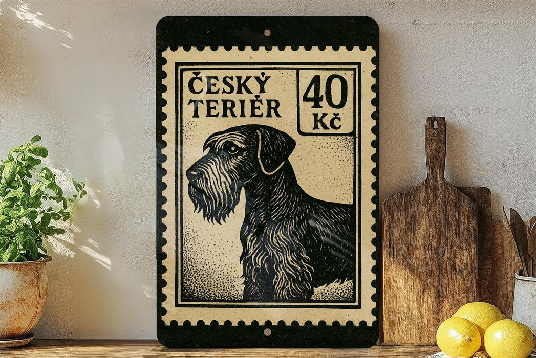 a black and white illustration of a terrier dog, which appears to be a Césky Terrier, on a black and white postage stamp. The stamp is framed with a black border and has the text "Césky Terrier" and "40 Kč" printed on it. The stamp is placed on a wooden surface, and there are some kitchen utensils, such as a knife and a spoon, visible in the background.
