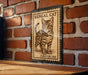 A vintage-style metal stamp featuring a Bengal cat illustration, mounted on a brick wall.
