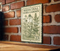 a metal sign with a brick wall background, displaying the text "MEDICINAL HERB GARDEN" and an illustration of various herbs and plants.