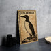 a wooden postcard with a bird illustration, placed on a table next to some black camera lenses.