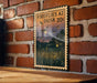 A framed poster with a painting of fireflies and a night sky on a brick wall.