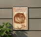 A 25c postage stamp featuring a hamster on a brown background, mounted on a wall next to a plant.