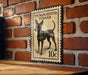 A vintage-style metal stamp depicting a toy Manchester Terrier, with the text "TOY MANCHESTER TERRIER" and the denomination "10c".