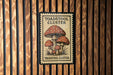 A sign with the text "TOADSTOOL CLUSTER" and an illustration of three mushrooms is displayed on a wooden wall.
