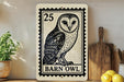 A barn owl illustration on a 25-cent stamp-like frame, placed on a wooden surface next to a wooden cutting board and some lemons.