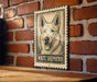 A wooden table with a framed image of a white shepherd dog on it, mounted on a brick wall.
