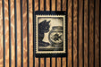 A black and white illustration of a cat sitting next to a fishbowl on a wooden surface.