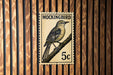 A vintage postage stamp featuring a bird, likely a Mockingbird, perched on a branch.