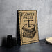 A vintage-style metal sign with the text "FLOWER PRESS" and an illustration of a flower press is displayed on a table.