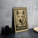 A framed illustration of a white shepherd dog is displayed on a wall, accompanied by a stack of black camera lenses and a white dish.