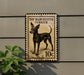A toy Manchester Terrier dog is depicted on a postage stamp-like sign, mounted on a wall.