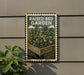 a raised bed garden sign with a plant illustration, mounted on a wall next to a plant.
