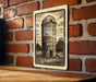 A black and white illustration of a tall cylindrical structure, resembling a barn or silo, is mounted on a brick wall.