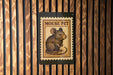 A wooden wall with a framed image of a mouse, which appears to be a postage stamp or a decorative piece.