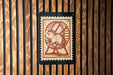 A stamp-like image of a hamster running on a wheel is displayed against a wooden background.