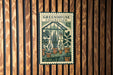 A vintage-style stamp or label with the text "GREENHOUSE COLLECTION" and the number "42" on it, hanging on a wooden wall.