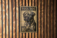 A metal stamp with a dog on it, mounted on a wooden wall.
