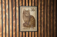 A 30c American curl postage stamp is displayed on a wooden wall.