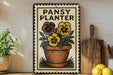 A framed sign with a potted plant and yellow and purple flowers, placed on a wooden shelf next to a wooden cutting board and a potted plant.
