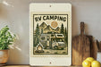 a wooden shelf with various items, including a potted plant, a wooden cutting board, and a small RV-style camper. The camper is depicted in a vintage-style illustration, with a campfire and mountains in the background. The text "RV CAMPING" is prominently displayed on the image.