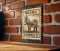 a sign with a donkey illustration on it, mounted on a brick wall.