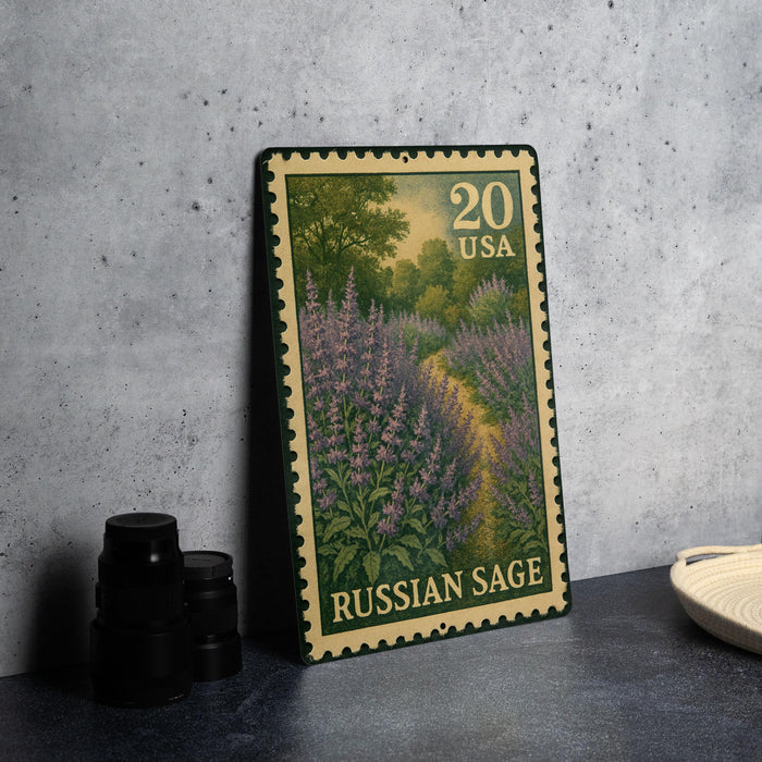 A metal stamp depicting a field of purple flowers, with the text "Russian Sage" printed on it, placed on a gray surface next to some black camera lenses.