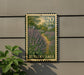 A postage stamp featuring a field of purple flowers, with the text "Russian Sage" printed on it. The stamp is mounted on a wall, and there is a plant next to it.