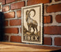 a wooden table with a framed illustration of a ram on it, mounted on a brick wall.