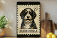 A framed image of a Bernoodle dog, a breed of small, curly-haired, mixed-breed dog, is displayed on a shelf next to a wooden cutting board and some lemons.