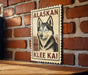 A wooden table with a wooden border, against a brick wall. There is a framed poster of a dog, specifically an Alaskan Klee Kai, hanging on the wall.
