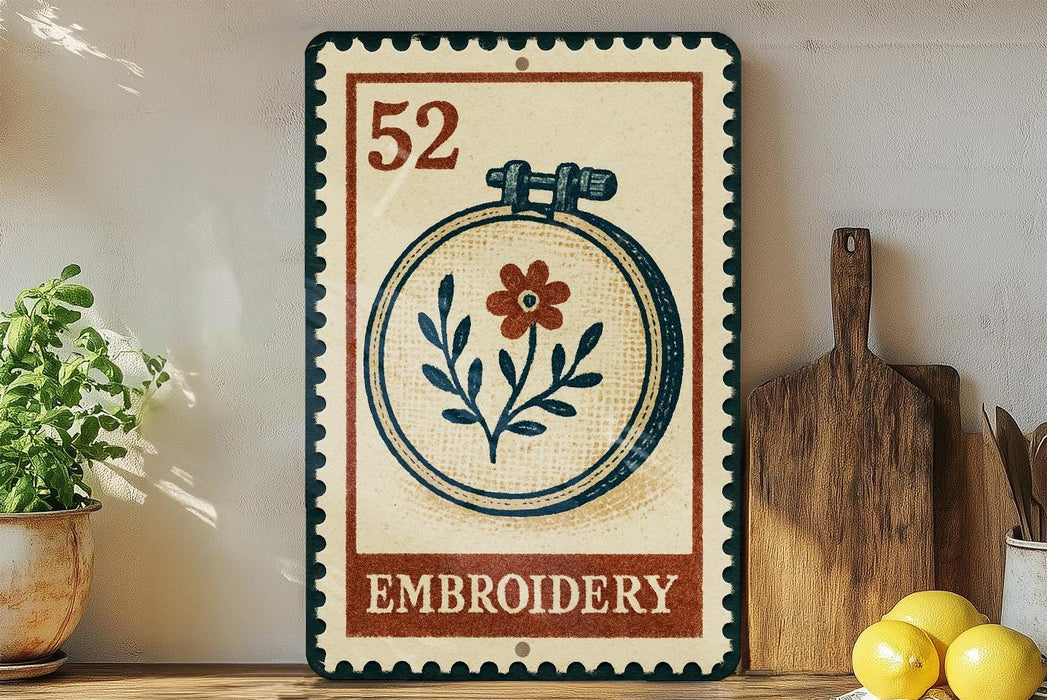 a vintage-style sign with a floral embroidery design, placed on a wooden surface next to a wooden cutting board and a potted plant.