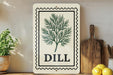 a decorative sign with a dill plant illustration, placed on a wooden surface next to a wooden cutting board and some lemons.