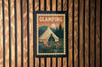 A vintage-style poster of a tent and camping scene is displayed on a wooden wall.