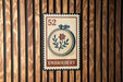 a vintage-style stamp or sign with the word "EMBROYERY" printed on it, mounted on a wooden wall.