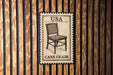 A wooden wall with a framed image of a cane chair, which appears to be a decorative piece or a sign.