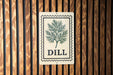 A sign with the word "DILL" on it is displayed on a wooden wall.