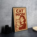 A metal sign with a woman hugging a cat, accompanied by the text "CAT MOM".