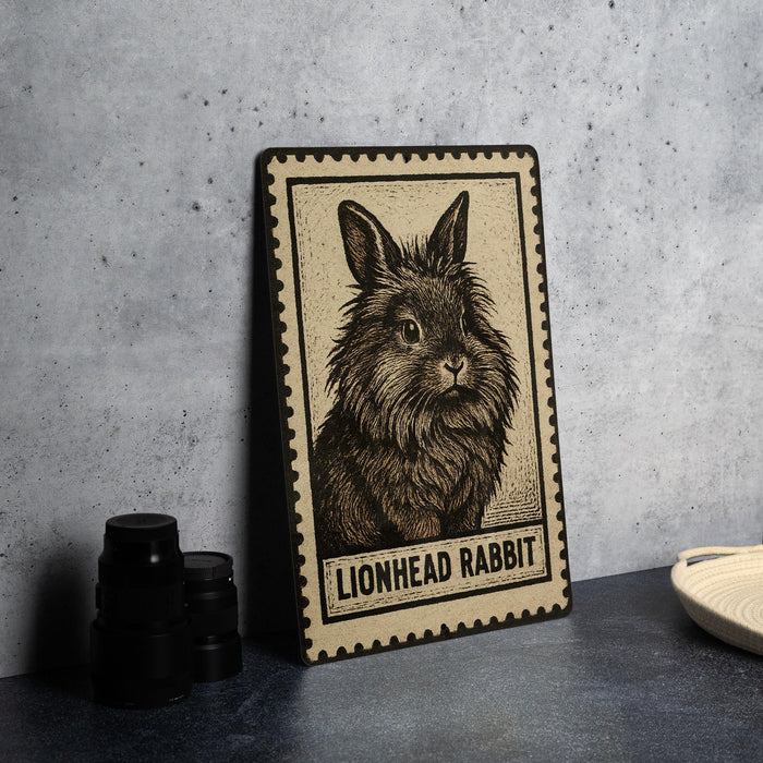 A framed illustration of a lionhead rabbit is displayed on a table, accompanied by a stack of black camera lenses and a white plate.