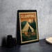A framed poster of a tent and camping scene is displayed on a wall, with a stack of black camera lenses and a white dish visible to the side.