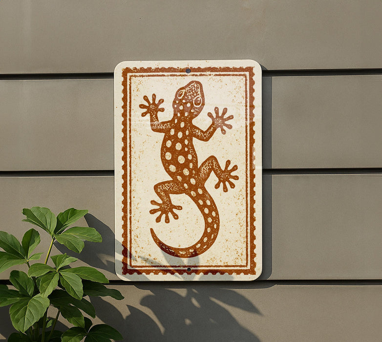 a sign with a lizard design on it, mounted on a wall next to a plant.