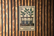 A 5c postage stamp with a drawing of three plant growth stages in bottles, mounted on a wooden wall.