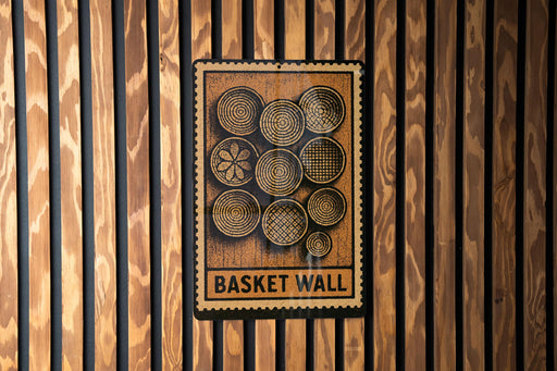 a sign with the text "Basket Wall" and a design of concentric circles on a wooden background.