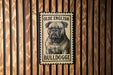 A metal sign featuring a bulldog illustration is mounted on a wooden wall.