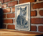 A wooden sign with a black and white illustration of a cat, mounted on a brick wall.