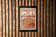 a wooden wall with a vintage-style stamp or sign that reads "FARMHOUSE PIE" and depicts a pie on a plate.